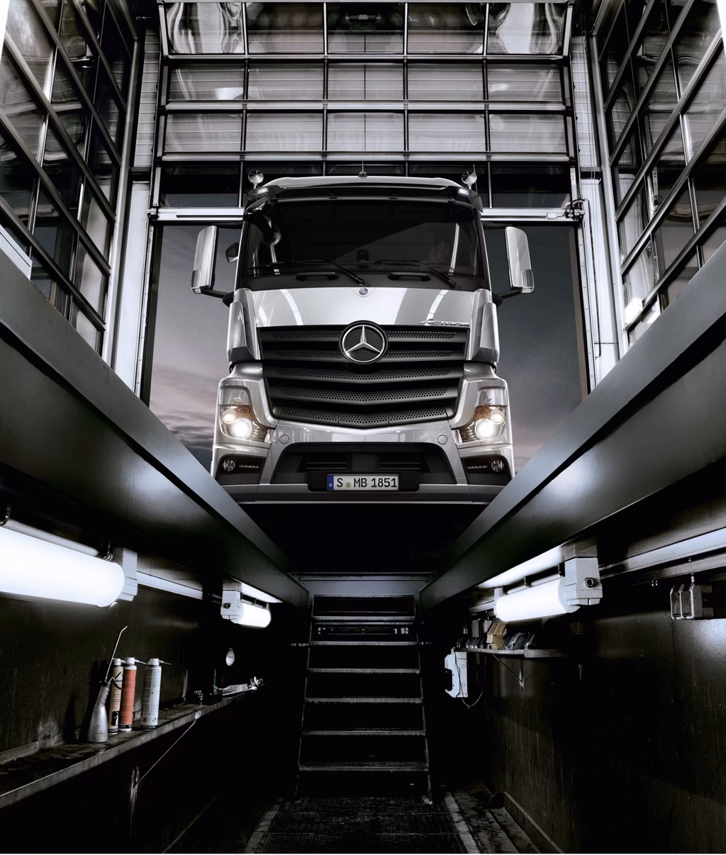 Mercedes-Benz Lastwagen in einer Werkstatt von oben fotografiert, mit geöffneter Motorhaube und Wartungsbereich.